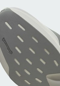 Σόλα γκρι αθλητικού παπουτσιού με πολλαπλές οβάλ εγκοπές για κράτημα και λογότυπο Continental χαραγμένο στην υφασμένη επιφάνεια από καουτσούκ.