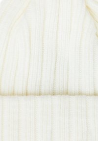 Berretto lavorato a maglia bianco con una texture a coste, caratterizzato da un risvolto e filato morbido, creando un aspetto accogliente e una vestibilità aderente.
