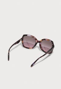 Lunettes de soleil à motif écaille de tortue violet avec un design surdimensionné et angulaire, dotées de verres dégradés et de branches fines avec une finition lisse.