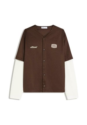 Cămașă maro cu nasturi, cu mâneci albe lungi dedesubt, având textul „offroad” pe partea stângă și o etichetă „Always Inspired” pe pieptul drept.