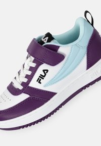 Sneaker bianco e viola con una fascia in velcro, caratterizzata da un accento blu chiaro, materiali testurizzati e una suola con motivo. Logo Fila visibile.