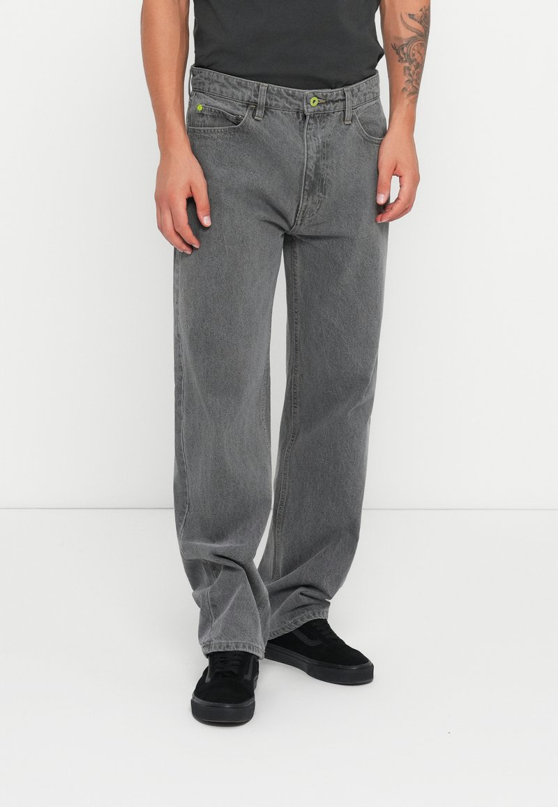 Grå denim jeans med en afslappet pasform, der har grønne detaljer og forlommer. Materialet har en blød tekstur med en let afdæmpet finish.