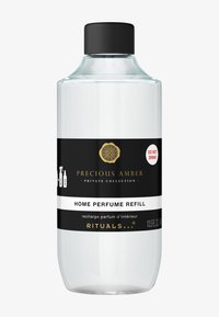 Przezroczysta szklana butelka z czarną nakrętką, z etykietami w czerni i bieli. Tekst zawiera "UZUPEŁNIENIE PERFUM DO DOMU" oraz etykietę ostrzegawczą.