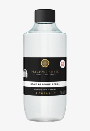 Przezroczysta szklana butelka z czarną nakrętką, z etykietami w czerni i bieli. Tekst zawiera "UZUPEŁNIENIE PERFUM DO DOMU" oraz etykietę ostrzegawczą.
