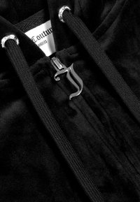 Černá mikina z veluru s tlustými šňůrkami, stříbrnými očky a stylizovaným stříbrným jezdcem na zip ve tvaru písmene "J".