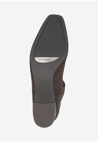 Semelle de chaussure en daim marron avec un design effilé, présentant une base en caoutchouc noir texturé et un accent logo en argent. Fini lisse dans l'ensemble.