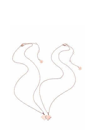 Two rose gold necklaces with puzzle piece pendants that fit together, each chain has a small flower-shaped charm near the clasp.