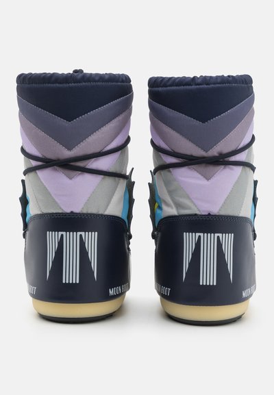Sinised ja hallid suusasaapad, millel on chevroni mustrid, pehme krae, mustad paelad ja tekstureeritud kummikreen. Bränding kandadel.