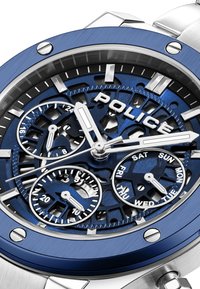 Orologio da polso con un design scheletrico, tonalità blu e argento, multiple sottofasi e una finitura testurizzata sulla lunetta e sul bracciale.