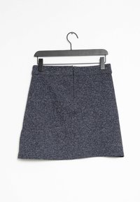 Jupe mini en tweed bleu foncé avec une texture subtile, fermeture éclair à l'arrière et coupe droite, accrochée sur un cintre noir.