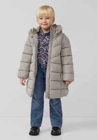 Szara puchowa kurtka z kapturem wykończonym futerkiem, z pikowanym wzorem i sercowym akcentem. Połączona z kwiecistą bluzką i jeansami.