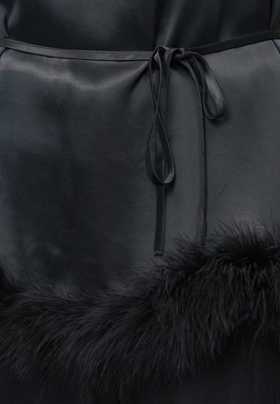 Haină neagră din satin cu talie strânsă printr-o panglică legată și tiv cu blană sintetică moale, creând un contrast de texturi.