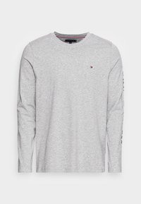 Lichtgrijs shirt met lange mouwen gemaakt van katoen. Heeft een ronde hals, een klein logo op de borst en een tekstafbeelding langs de linkermouw.