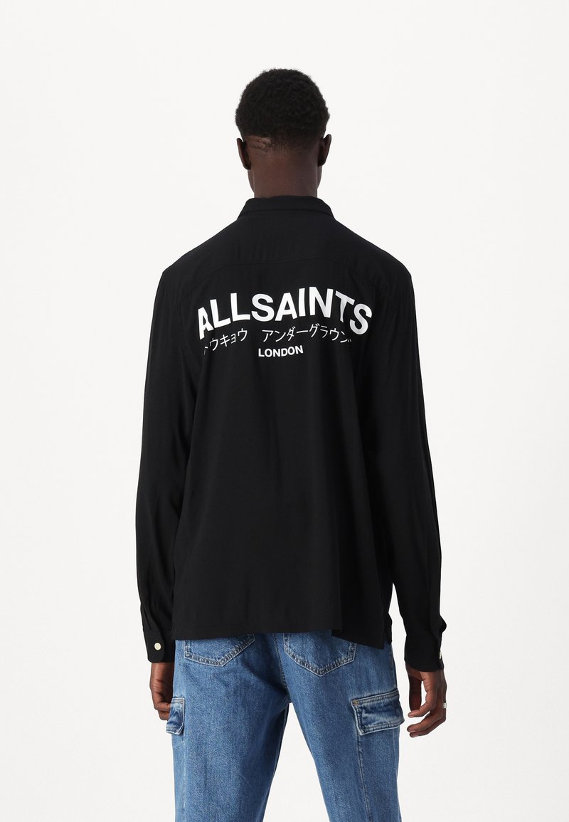 Zwarte longsleeve shirt met kraag, voorzien van grote witte tekst "ALLSAINTS" en "LONDON" op de achterkant; soepele stof, ontspannen pasvorm.
