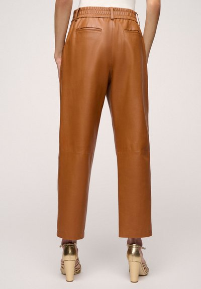 Brown leather pants with an elastic waistband, side pockets, and a straight-leg design, paired with gold high-heeled sandals.