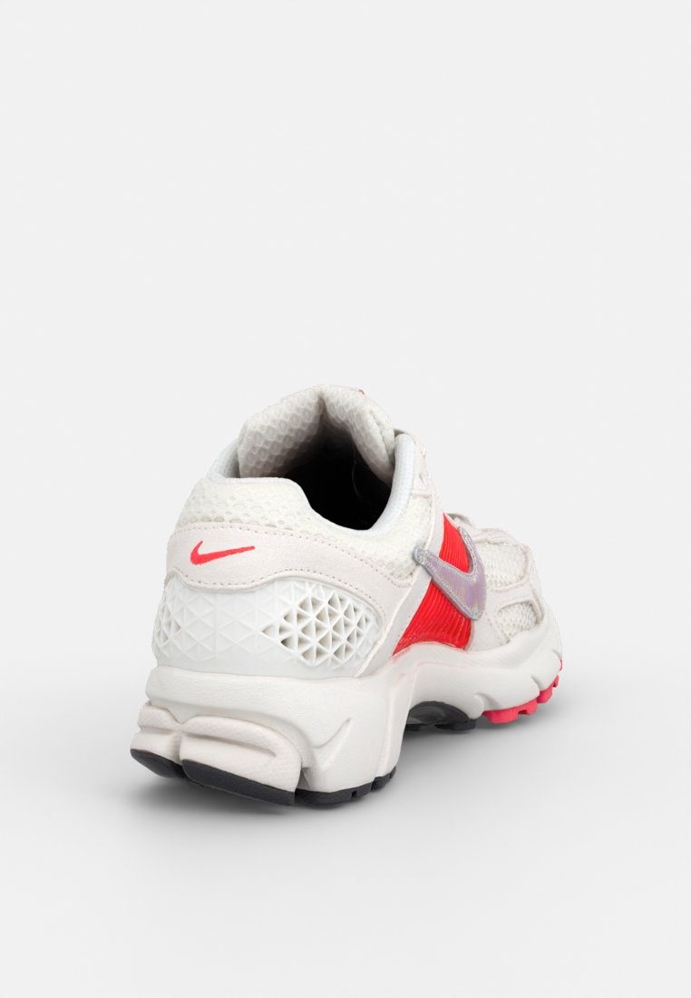Baskets Nike blanches et rouges avec une tige en maille texturée, un col rembourré et des motifs géométriques sur le côté. Semelle extérieure en caoutchouc avec des accents roses.