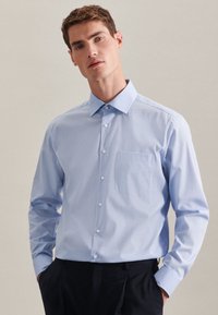 Light blue button-up shirt with long sleeves, a collar, and a chest pocket. Made of soft fabric with a smooth texture.