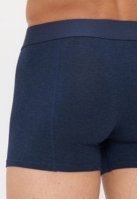 Dunkelblaue Baumwoll-Shorts mit glattem Bund, versehen mit flachen Nähten und einer enganliegenden Form für zusätzlichen Komfort.