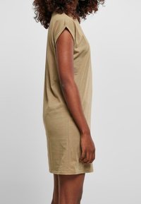 Khaki sukienka T-shirt z krótkimi podwiniętymi rękawami, dopasowany krój, miękka bawełniana tkanina oraz długość do kolan. Gładka faktura i minimalne detale.