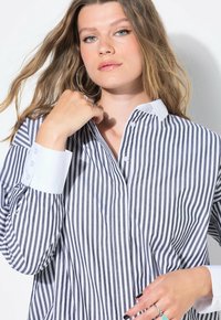 Camicia a righe blu navy e bianca, con colletto a ribattuta, maniche lunghe con polsini bianchi a contrasto e vestibilità comoda.