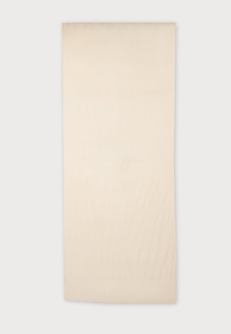 Tapis rectangulaire couleur crème avec des motifs subtils en relief de lignes ondulées sur fond blanc.