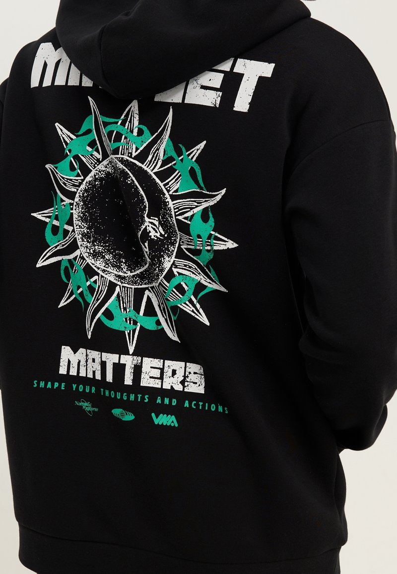 Sweat à capuche noir avec un graphique d'une figure centrale texturée entourée d'épines et de flammes vertes, et un texte qui dit "Matters" et "Shape your thoughts."