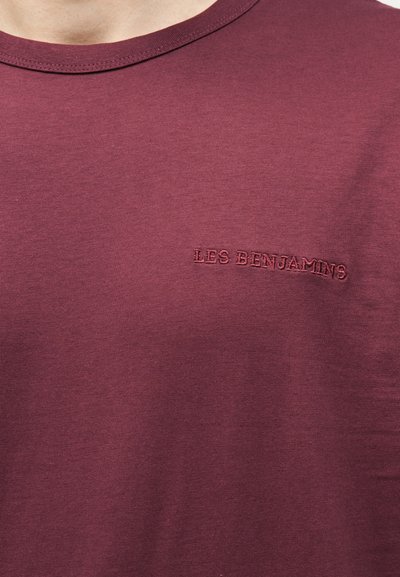 Μπλούζα με στρογγυλή λαιμόκοψη σε μπορντό χρώμα, με μικρό κεντημένο κείμενο "LES BENJAMINS" στην αριστερή πλευρά του στήθους.