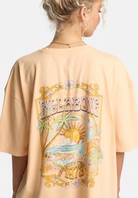 Μπλούζα Billabong oversized από απαλό βαμβάκι σε χρώμα ροδάκινο, με πολύχρωμο γραφι κό σχέδιο που απεικονίζει φοίνικες, ήλιο και λουλουδένιες λεπτομέρειες στην πλάτη.