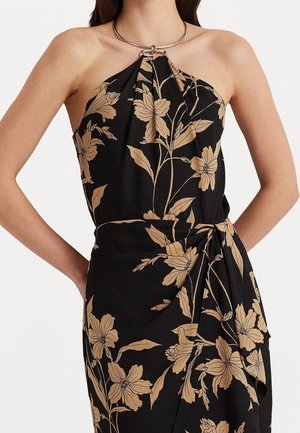 Sort halterneck-kjole med beige blomsterprint, samlet ved halsen med en metalring og bundet med en sidesløjfe i taljen.