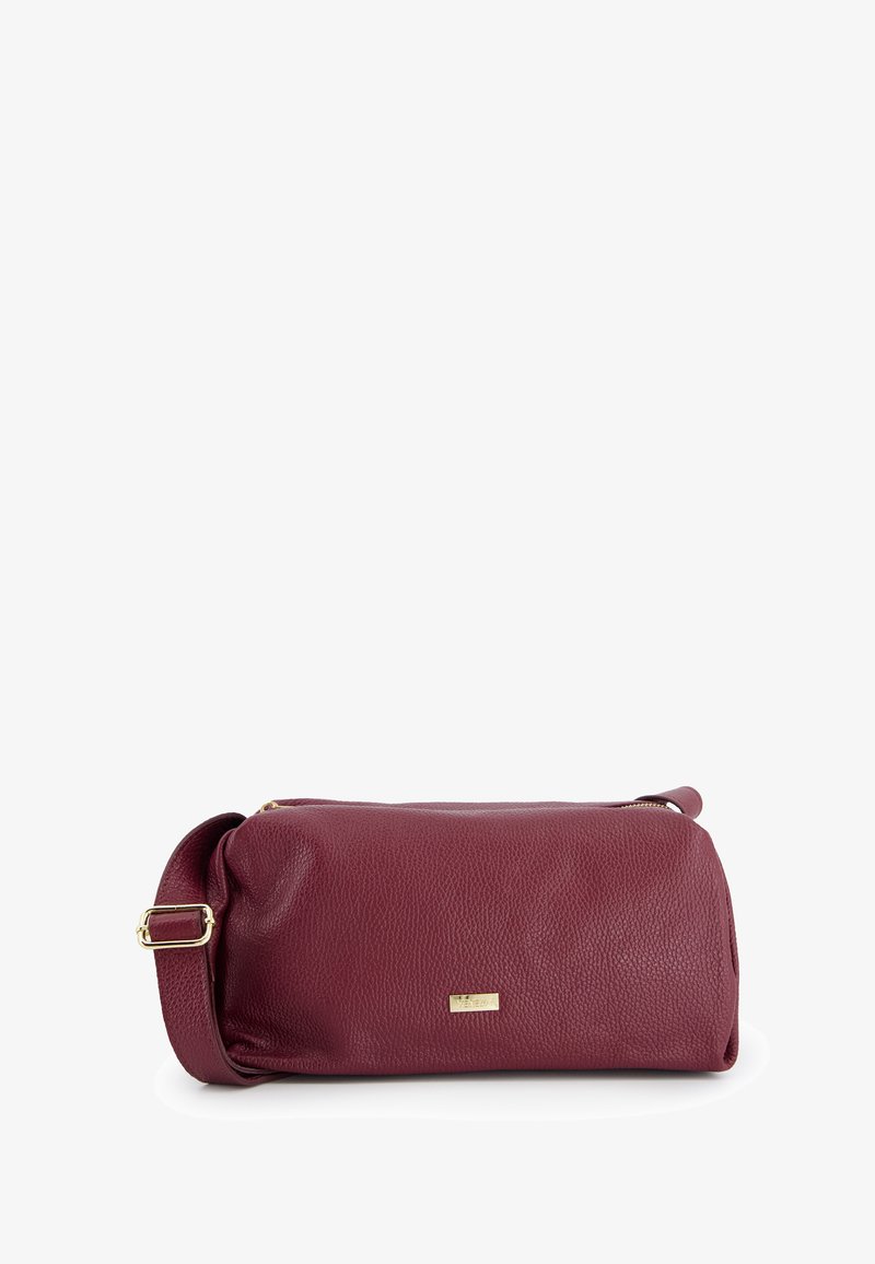 Burgundy leather crossbody bag with a structured cylinder shape, zipper closure, gold hardware accents, and a detachable strap.