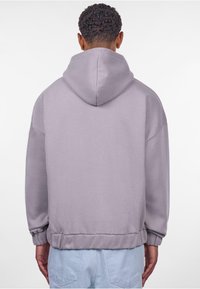 Hellblaue Kapuzenjacke mit weicher Textur, ausgestattet mit einer Kordelzugkapuze, gerippten Bündchen und lässiger Passform. Ansicht von hinten zeigt ein minimalistisches Design.