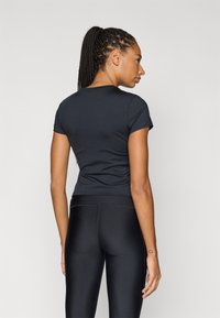 Black fitted T-shirt with short sleeves, smooth texture, and a round neckline, paired with black high-waisted leggings.