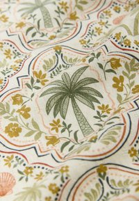 Tissu avec un motif répétitif de palmiers verts et de fleurs jaunes dans des cadres rectangulaires arrondis sur un fond crème.