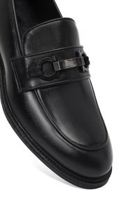 Schwarze Lederloafer mit glatter Oberfläche. Verfügt über einen dekorativen Riemen mit metallischem Akzent und Steppnähten entlang der Kanten.