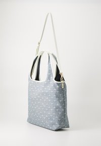 Vaaleansininen laukku, jossa on kuvioitu ulkopinta, valkoinen reunus, kaksinkertaiset kahvat ja irrotettava olkahihna. Silkinpehmeä pinta ja jämäkkä muoto.