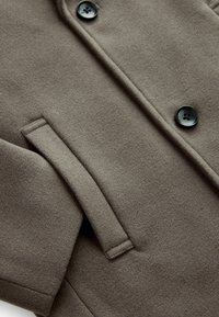 Abrigo de lana gris con botones negros, con una textura suave y un bolsillo lateral, diseñado con un corte clásico.