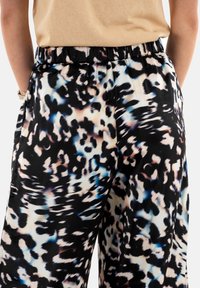 Pantaloni neri fluidi con una stampa animale astratta multicolore, dalla texture morbida, con vita elastica e design a gamba larga.