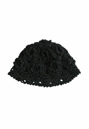 Schwarze gehäkelte Mütze mit Blumenmuster und wellenförmigem Rand, von oben auf weißem Hintergrund gesehen.