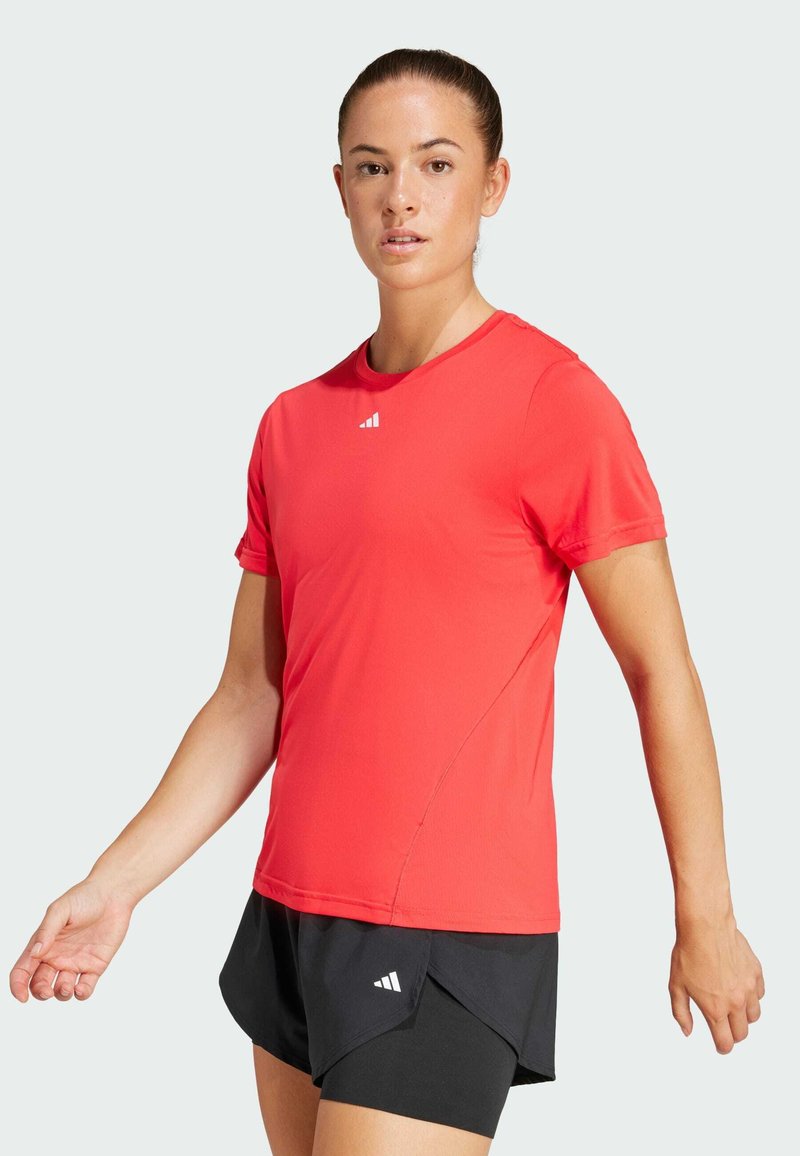 Red short-sleeve athletic shirt with crew neckline, made of lightweight fabric. Features Adidas logo on the chest and is paired with black shorts.