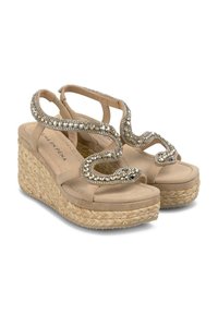 Sandali con zeppa beige con base in juta intrecciata. Presentano una fascia decorativa, scintillante a forma di serpente con piccole perline trasparenti e paillettes.