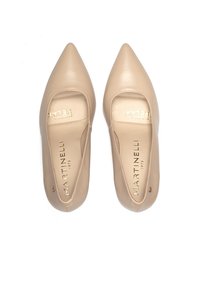 Zapatos beige de piel sin cordones con punta afilada, con un amplio panel elástico y letras doradas en la plantilla. Textura suave.