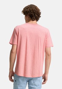 Camiseta de manga corta en rosa claro, hecha de una tela suave con textura jaspeada. Cuello redondo clásico y corte relajado, sin gráficos.
