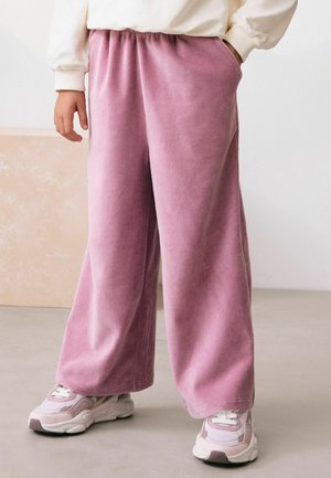 Lyserøde corduroy vide bukser med elastisk talje og sidelommer, parret med klumpede hvide og lyserøde sneakers.