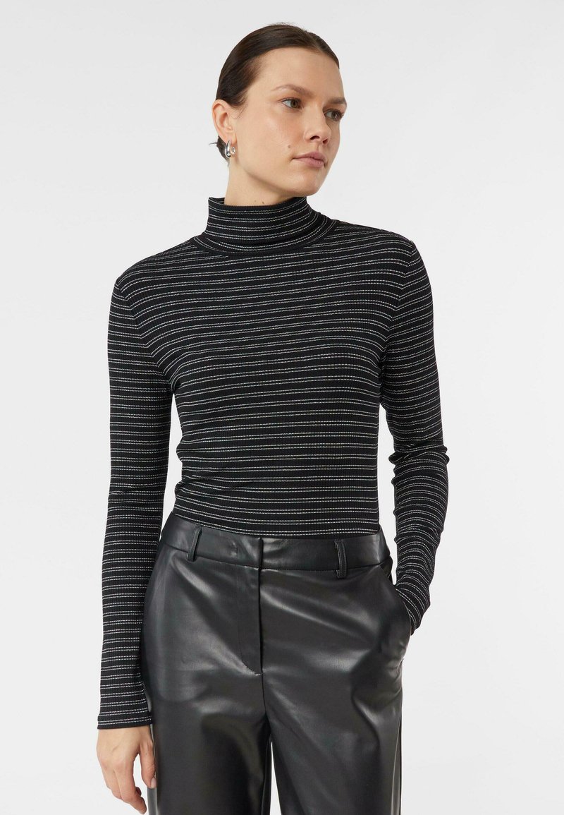 Czarny golf w paski z długimi rękawami, ozdobiony poziomymi metallicznymi paskami. Połączony z czarnymi, wysokim stanem, skórzanymi spodniami.