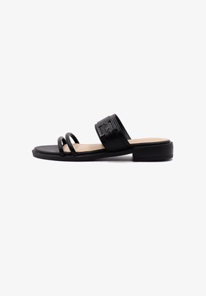 Zwarte slip-on sandaal met een platte zool, voorzien van twee gebogen banden en een brede band met reliëfdetails. Glad leren textuur.