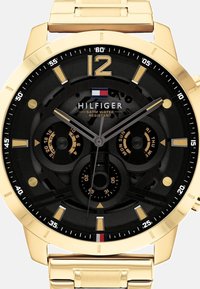Montre en acier inoxydable doré avec un cadran noir, dotée d'accents dorés, de trois sous-cadrans pour le jour et la date, et d'une étanchéité de 5 ATM.