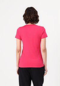 Kortærmet t-shirt med rund hals i lyserød bomuldsstof, med en tætsiddende silhuet og glat tekstur. Ingen synlige mønstre eller dekorationer.