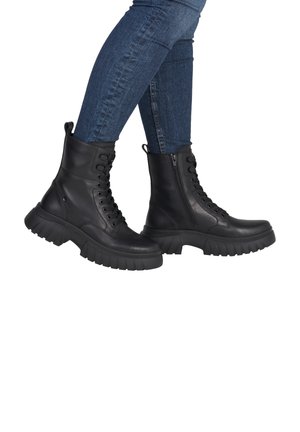 Bottes de combat en cuir noir avec un laçage à l'avant et une fermeture éclair sur le côté, dotées d'une semelle en caoutchouc épaisse et d'accents texturés.