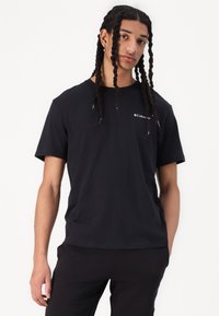 Sort kortærmet t-shirt lavet af bomuld, med rund hals og et lille hvidt logo i det øverste venstre brystområde. Glat tekstur.
