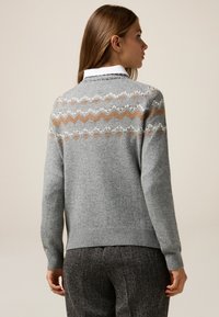 Suéter gris de punto con un patrón de zigzag y diamante en beige y blanco, con puños y dobladillo acanalados, mostrado desde la parte de atrás.